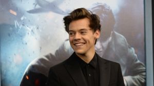 Harry Styles är en av artisterna som uppträder på galan. Porträttbild av Harry Styles med en reklamaffisch för filmen Dunkirk i bakgrunden.