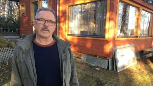 Tusbybon Jarmo Kyttänen tänker inte ge upp stuglivet, trots att han störs av flygbullret. Stugan ligger ungefär två kilometer från flygplatsen. Medelålders man står utanför en stuga i trä.