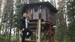 Mats Grönblom på trappan till ett av skogsbyns trädhus, där besökare kan övernatta. Mats Grönholm klättrar upp i en stuga uppe i ett träd