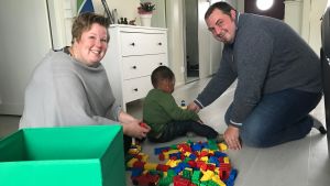 Familjen Pettersson njuter av hemmalivet och drömmer om ett syskon från Sydafrika. Åsa och Martin bygger lego med Denzel på golvet.