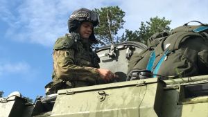 Finland deltar i övningen med elva bepansrade fordon och två hornet jaktplan. Finländsk rekryt uppe på bepansrat militärfordon.