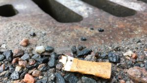 Tupakantumppi lojuu maassa sadevesiviemärin vieressä