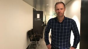 Centralvalnämndens ordförande Robert Sundström. Robert Sundström står i en korridor. Till vänster en rad stolar och en dörr på glänt.