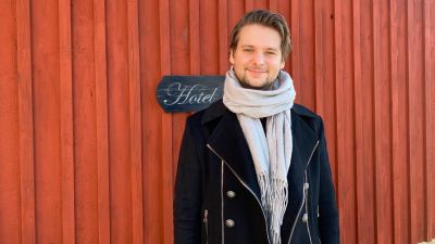 Man vid rödmålad husvägg.