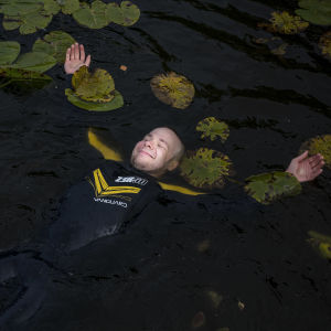 Juha Riikonen kelluu märkäpuku päällä vedessä lumpeiden seassa.