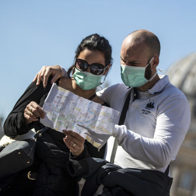 Två personer i munskydd står och tittar på en karta i Italien. 