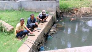 Jakartalaiset kalamiehet onkimassa moottoritien viereisestä lammesta