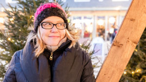 Soile Suvanto seisoo Oulun Rotuaarilla kuusien katveessa.