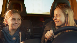 Linnea fick mycket hjälp under inspelningarna av Paula Vesala, som spelar mamman i filmen. mor och dotter ler mot varandra i framsätet på en bil.