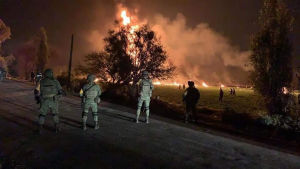 Soldater i förgrunden, en brand i bakgrunden efter att en oljeledning börjar brinna i delstaten Hidalgo i Mexiko.