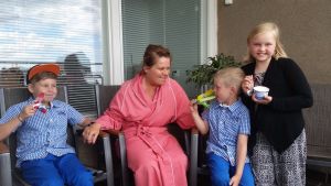 Åtta månader efter att Project Liv grundas och Nina Brännkärr-Friberg är lyckligare än på länge hittar läkarna en enorm tumör i hennes hals som går ända upp till skallen. Nina Brännkärr-Friberg i sjukhuskläder tillsammans med barnen.