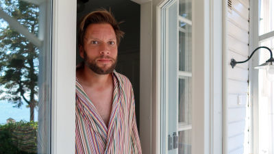 Porträtt av Tuomas Routto som står i dörröppningen till sitt hus i Hangö.