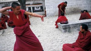 Tibetanska munkar. En tibetansk munk intar en pose under en religiös debatt vid klostret Sera i Lhasa.