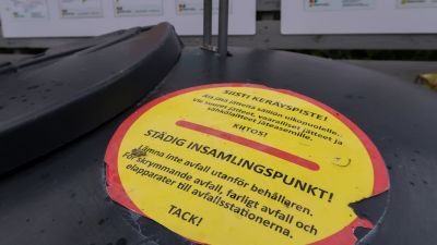 Bild av en påklistrad skylt på en avfallscontainer som uppmanar att inte lämna avfall utanför behållaren.