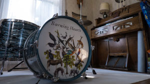 Till vänster ett trumset med bilder på djur och texten Burning Hearts och till vänster en tramporgel.