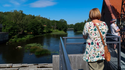 Kvinna som blickar ut över Svartån från en bro i Billnäs.
