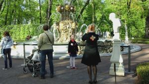 Tyttö poseeraa äidille suihkulähteen edessä Pietarin Kesäpuistossa
