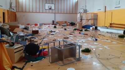 En gymnastiksal som blivit utsatt för skadegörelse. På golvet ligger en massa bråte.