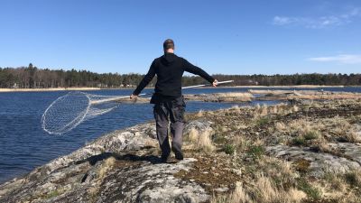 Man med hov på klippa vid strand.