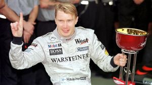 Mika Häkkinen säkrar båda sina VM-titlar med seger i säsongens sista deltävling. Mika Häkkinen med VM-pokalen 1998.