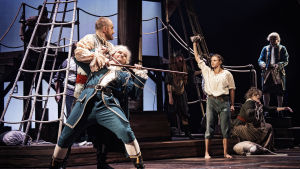 Maktkamp på Hispaniola. Long John Silver ( Niklas Åkerfelt) attackerar Squire Trelawney (Alfons Röblom). Foto från Skattkammarön på Svenska Teatern.