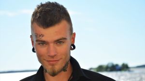 David Björkström var lyssnarnas sommarpratare ifjol. Ung man med liten tatuering i pannan ser in i kameran.