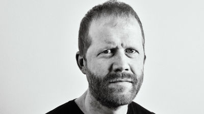 En svartvit porträttbild av Andreas Malm, som tittar in i kameran med allvarsam blick.