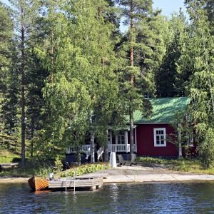 Kesämökki, laituri ja soutuvene Saimaalla.