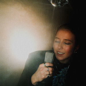 Det gäller att ta ikoniska bilder. Ilon fotograferad av Julian Riikonen. Ilon med mikrofon, under discokula.