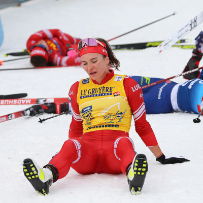 Tour de Skin voittanut Natalia Neprjajeva istuu lumella hengästyneenä. Taustalla selällään makaavia kilpailijoita kaikkensa antaneina.