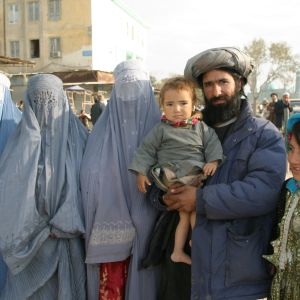 Afganistan, Kabul. Afganistanilainen perhe Kabulin kadulla. Naiset ovat pukeutuneet burkhaan, isä kantaa lasta sylissä.