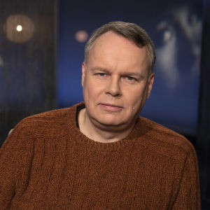 Professori Juho Saari Mediapoliksen studiossa Tampereella toimittaja Anne Flinkkilän vieraana, Juho istuu rennosti kuvassa ruskea villapaita yllään.