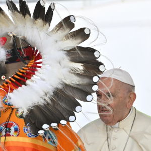 Påve Franciskus möter en person från urbefolkningen med fjäderhuvudbonad.