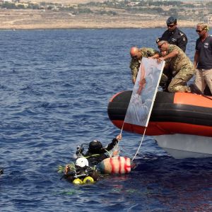 Dykare lägger ner ett minne för tragedin utanför Lampedusa i havet. Den 3 oktober var det ett år sedan katastrofen.