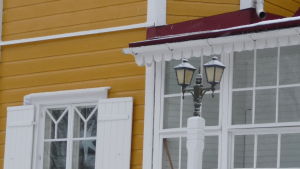 Mycket snickarglädje, fin glasveranda. detaljer på fasden på Villa Snäcksund, lite glasveranda, fönster med vita luckor, gul brädfodring
