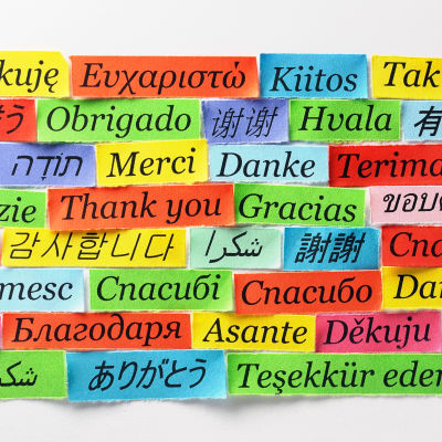 Lappar med ordet tack på många olika språk på en vägg.