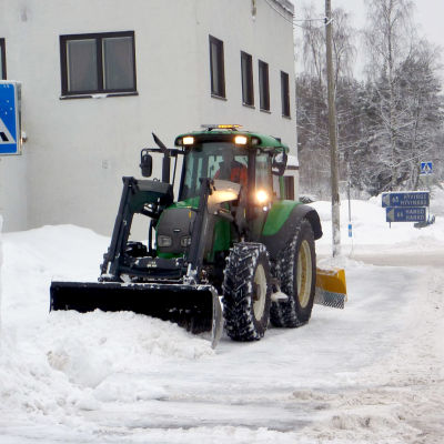 En traktor röjer bort snö på en trattoar i Svartå.