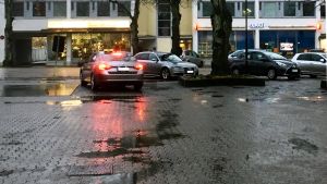 En taxibil och några andra bilar på ett regnigt gatu- och parkeringsområde i Ekenäs en novemberdag.