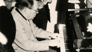 Pianotaiteilja Gerald Moore soittaa opiskelijoiden ympäröimänä.