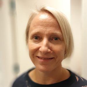Ensamhet är en subjektiv känsla, säger Emma Soveri. Alla kan emellanåt känna sig ensamma, Emma Soveri, en dam med blont, sidkammat hår i en blåsvart skjorta med rosa blommönster.