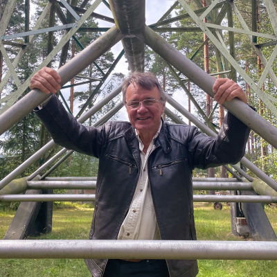 Stefan Blomqvist ler och tittar in i kameran. Han håller i stolparna på sitt vindkraftverk.