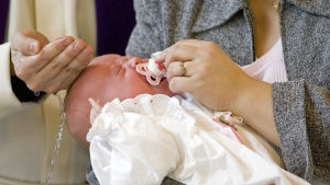 Ordna små förrättningar med bara några anhöriga närvarande. Arkivbild. präst döper en baby
