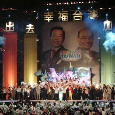 Taiwanesiskt valmöte. Människor på scen viftar med flaggor. 