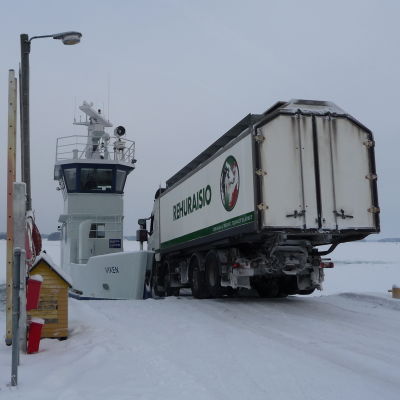En fodertransport kör ner för rampen ombord på förbindelsefartyget Viken i Granvik i Pargas. Havet är nästan helt instäckt.