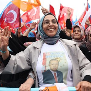 Huivipäiset Erdoganin kannattajat näyttävät käsimerkkejä lippumeren keskeltä vaalitilaisuudessa.