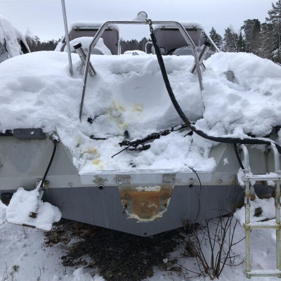 En båt täckt av snö där utombordsmotorn har tagits bort.