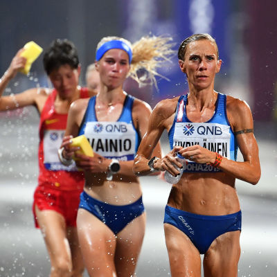 Alisa Vainio, Anne-Mari Hyryläinen och två andra maratonlöpare springer och förser sig med vatten samtidigt.