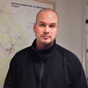 Matti Huttunen vill att vattenförsörjningen i Sibbo är trygg och säker. Ung man i mörkblå tröja framför en karta över en kommun.