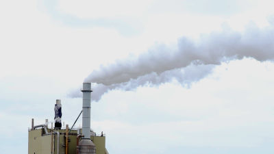 Grå rök som pyr ut ur en fabrikspipa vid en cellulosafabrik.