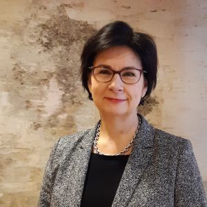Tanken och målsättningen är att behovet av internatboende inte ökar märkbart på grund av skolreformen, eftersom det är en dyr utgift, säger kanslichef Anita Lehikoinen vid Undervisnings- och kulturministeriet. Foto på kanslichef Anita Lehikoinen fotad mot ett konstverk med näverbark